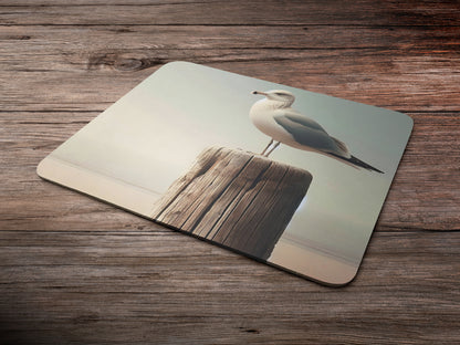 Seagull perched on a weathered wooden post by the beachmousepad mockup style 6