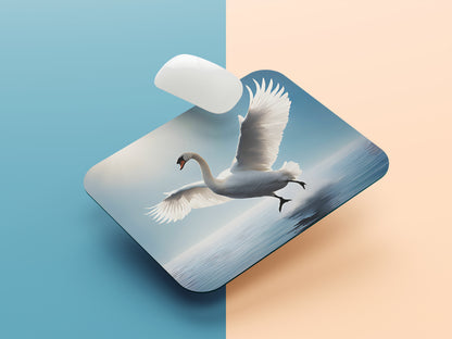 Swan in mid-flight, with its wings fully extended against a clear blue sky mousepad mockup style 1